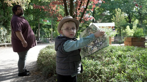 Raphael hält eine Karte des Zoos in der Hand und schaut in die Kamera.