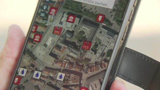 Ein Handybildschirm zeigt einen Stadtplan mit verschiedenen Symbolen