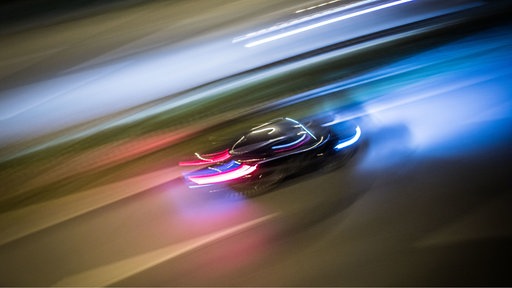Ein Auto rast nachts auf der Autobahn.