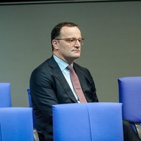 Jens Spahn sitzt im Bundestag, vor ihm sind die Stuhlreihen leer