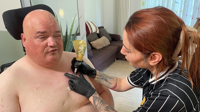 Eine Frau tätowiert einen Mann.