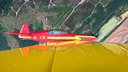 Ein Kleinflugzeug fliegt schräg über Felder hinweg.