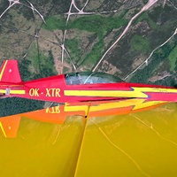 Ein Kleinflugzeug fliegt schräg über Felder hinweg.