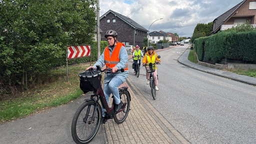 Mehrere Personen biegen auf ihren E-Bikes hintereinander in eine Straße ein.