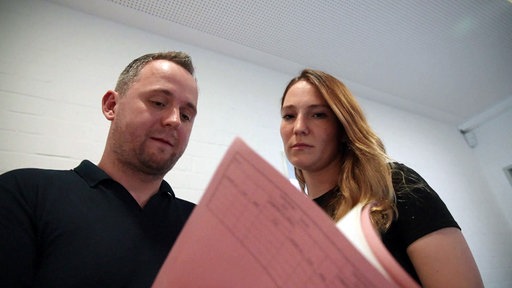 Ein Mann und eine Frau schauen sich einen Aktenhefter an.