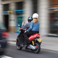 Zwei Personen fahren auf einem Motorroller