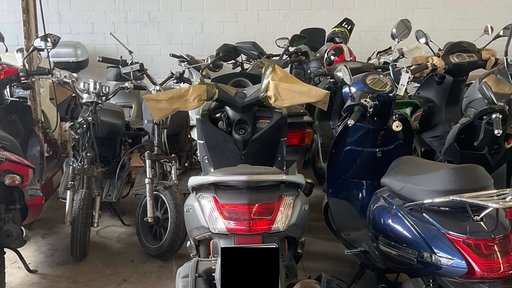 Einige Motorroller stehen in einer Halle