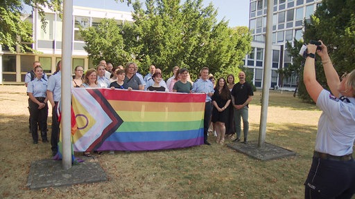 Eine Gruppe von Personen hält die Pride-Flagge hoch