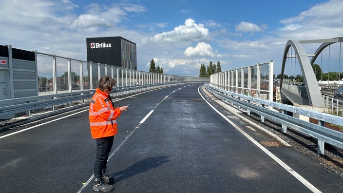 Eine Frau in Warnkleidung steht auf der neu gebauten Brücke der B51.
