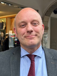 Ladenbesitzer Alexander Grümer steht vor seinem Laden am Prinzipalmarkt und lächelt.