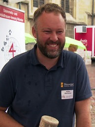 Steinmetz Robert Wennemer steht auf dem Domplatz und lacht.