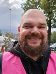 Joachim Bick, Mitorganisator Park(ing) Day Münster grinst mit pinker Warnweste in die Kamera