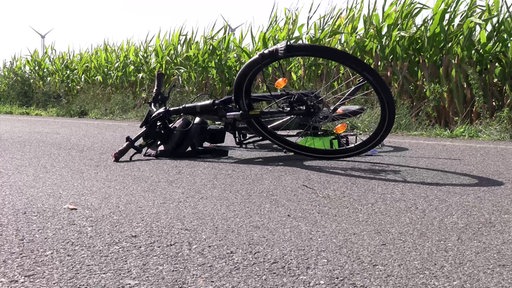 Ein kaputtes E-Bike liegt auf einer Landstraße.