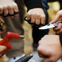 Jugendliche Hände halten verschiedene Waffen in die Mitte.
