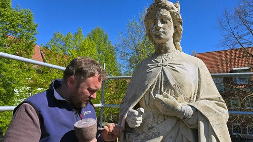 Restaurator Robert Wennemer an der St. Margaretha-Statue in Ostenfelde. Er schlägt alten Mörtel ab.