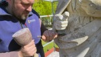 Nahaufnahme von Restaurator Robert Wennemer an der St. Margaretha-Statue in Ostenfelde. Er schlägt alten Mörtel ab.