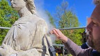 Restaurator Robert Wennemer arbeitet mit speziellem Werkzeug an der St. Margaretha-Statue in Ostenfelde.
