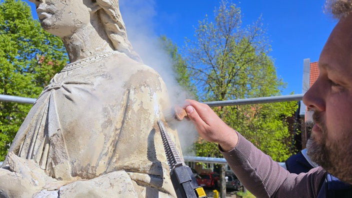 Restaurator Robert Wennemer arbeitet mit speziellem Werkzeug an der St. Margaretha-Statue in Ostenfelde.