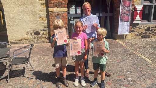 Eine Familie mit Urkunden in der Hand.