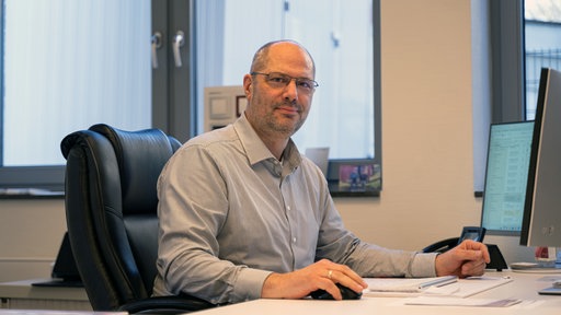 Stefan Raddant sitzt an einem Schreibtisch und schaut in die Kamera.