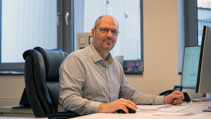 Stefan Raddant sitzt an einem Schreibtisch und schaut in die Kamera.