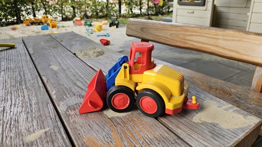 Ein Spielzeugbagger steht auf einem Holztisch