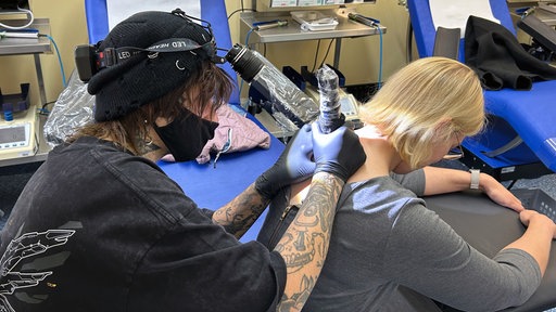 Ein Organspender Tattoo wird auf den Nacken einer Frau gestochen
