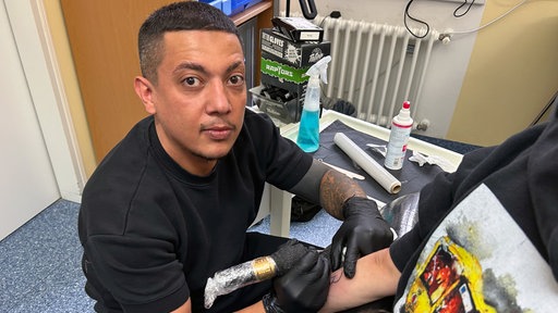 Ein Mann stciht ein Organspender Tattoo