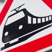 Ein dreieckiges Warnschild vor durchfahrenden Zügen.