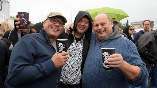 DreiToten Hosen-Fans im Regen lachen in die Kamera.