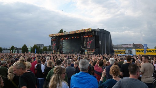 Das Publikum steht vor einer Konzertbühne auf der die Vorband "deine Cousine" spielt.