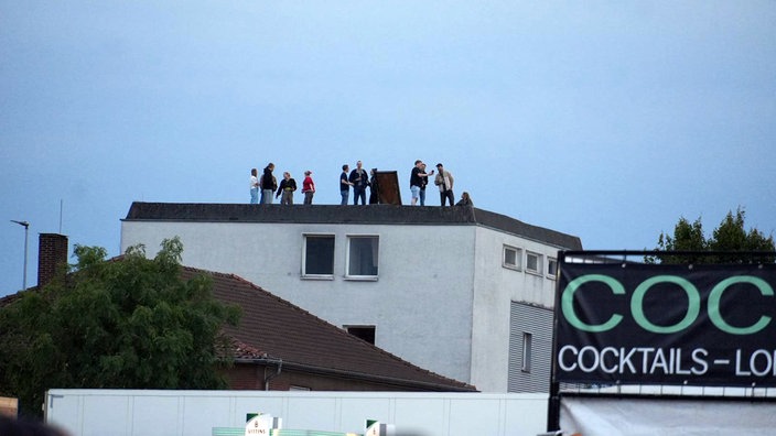 Fans schauen von einem benachbarten Haus auf das Konzert.