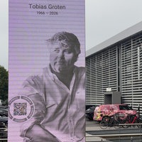 Bildschirm mit Bild von Tobias Groten mit Lebensdaten vor dem Tobit Gebäude.