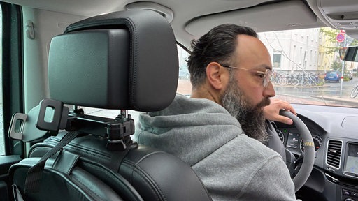 Ein Mann mit Brille fährt Auto