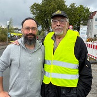 Zwei Männer mit Brille. Einer trägt eine Warnweste.