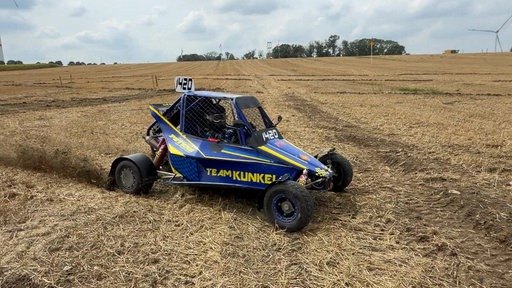 Ein Jugendlicher sitzt am Steuer eines Renn-Buggy, Hochgeschwindigkeits-Fahrzeug mit einem aufgesetzten Käfig zum Schutz des Fahrers. 