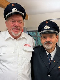 Zwei Feuerwehrmänner stehen nebeneinander. 