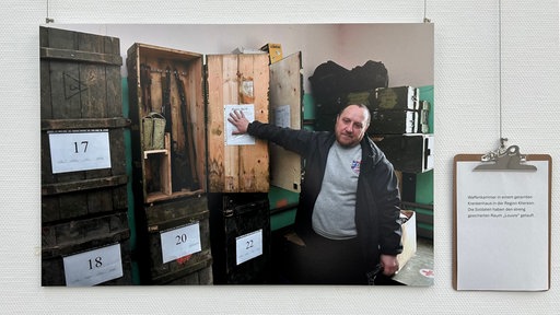 Fotografie an der Wand hängend mit Infotafel daneben.