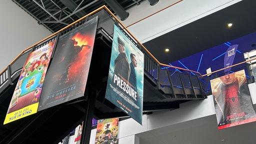 In der Eingangshalle des Kinos hängen Plakate der aktuell laufenden Filme.