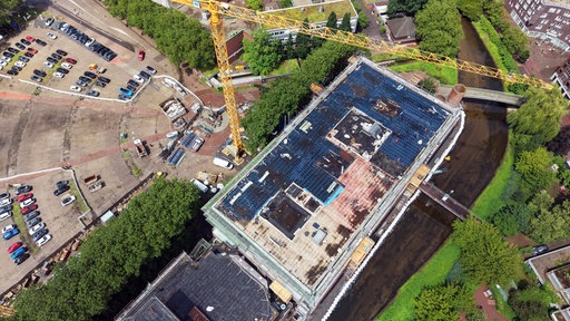 Aus der Luft sieht man das eingerüstete Rathaus mit Bau-Kränen direkt am Berliner Platz
