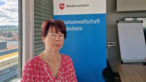 Staatsanwältin Christine Wotschke aus Hildesheim im Portrait vor einem Aufsteller der Staatsanwaltschaft