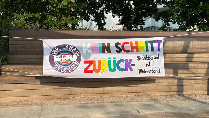 Ein helles Banner mit der Aufschrift "Kein Schritt zurück - Sichtbarkeit ist Widerstand. CSD Ahaus. 28.08.2026"