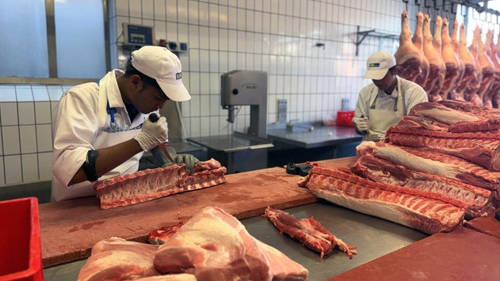 Zwei Azubis aus Indonesien bei der Arbeit in einer Fleischerei