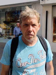 Ein Mann mit Rucksack schaut in die Kamera.