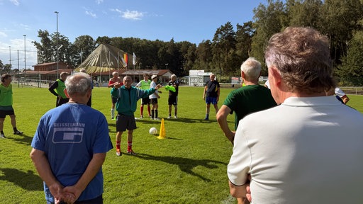 Das Team steht im Kreis und hört dem Trainer zu.