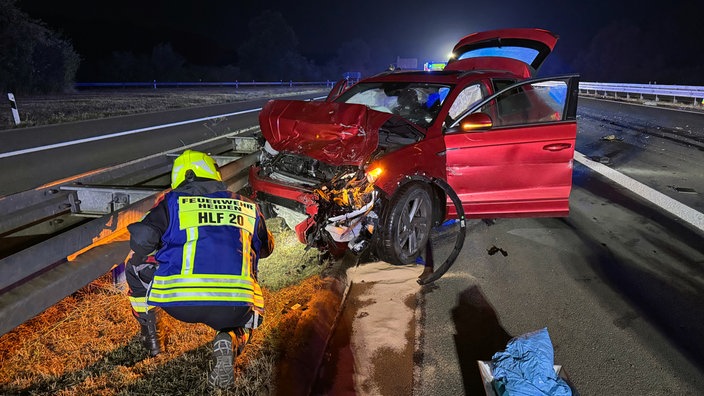Ein Feuerwehrmann inspiziert ein beschädigtes Auto nach einem Unfall.