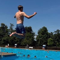 Ein Junge springt vom Einer ins Freibad.
