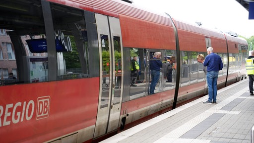 Zwei Menschen stehen am Bahnhof Coesfeld vor einer Regionalbahn