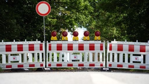 Straßenabsperrung mit Warnschild und Warnleuchten.