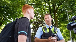Der Polizist Steffen Beckenhusen kontrolliert einen jungen Mann, der einen E-Scooter fährt.